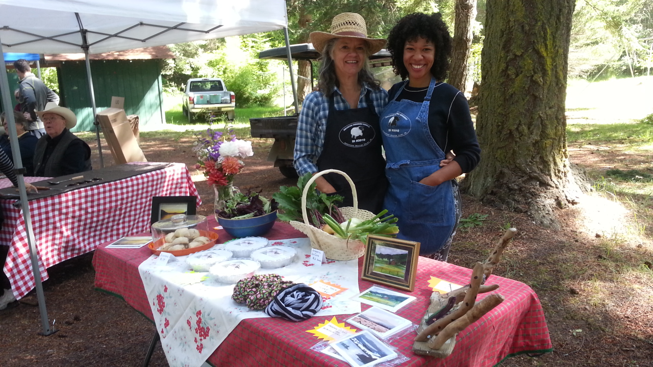 Two vendors pose with their display of goodies at the Decatur community market
