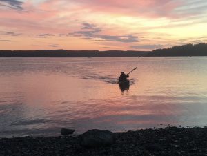 A kayaker coming in to shore during sunset